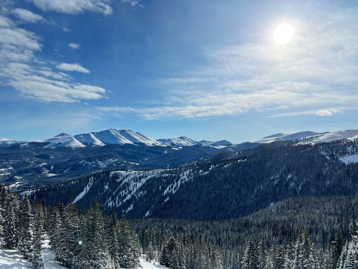 Snowy mountain ridges above a forested valley under a bright sky at Winter Park