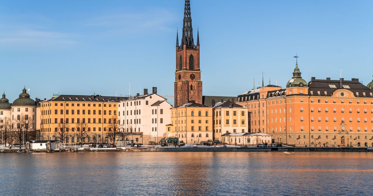Riddarholmen in Stockholm seen across the water, with the openwork iron spire of Riddarholm Church above yellow and orange palaces