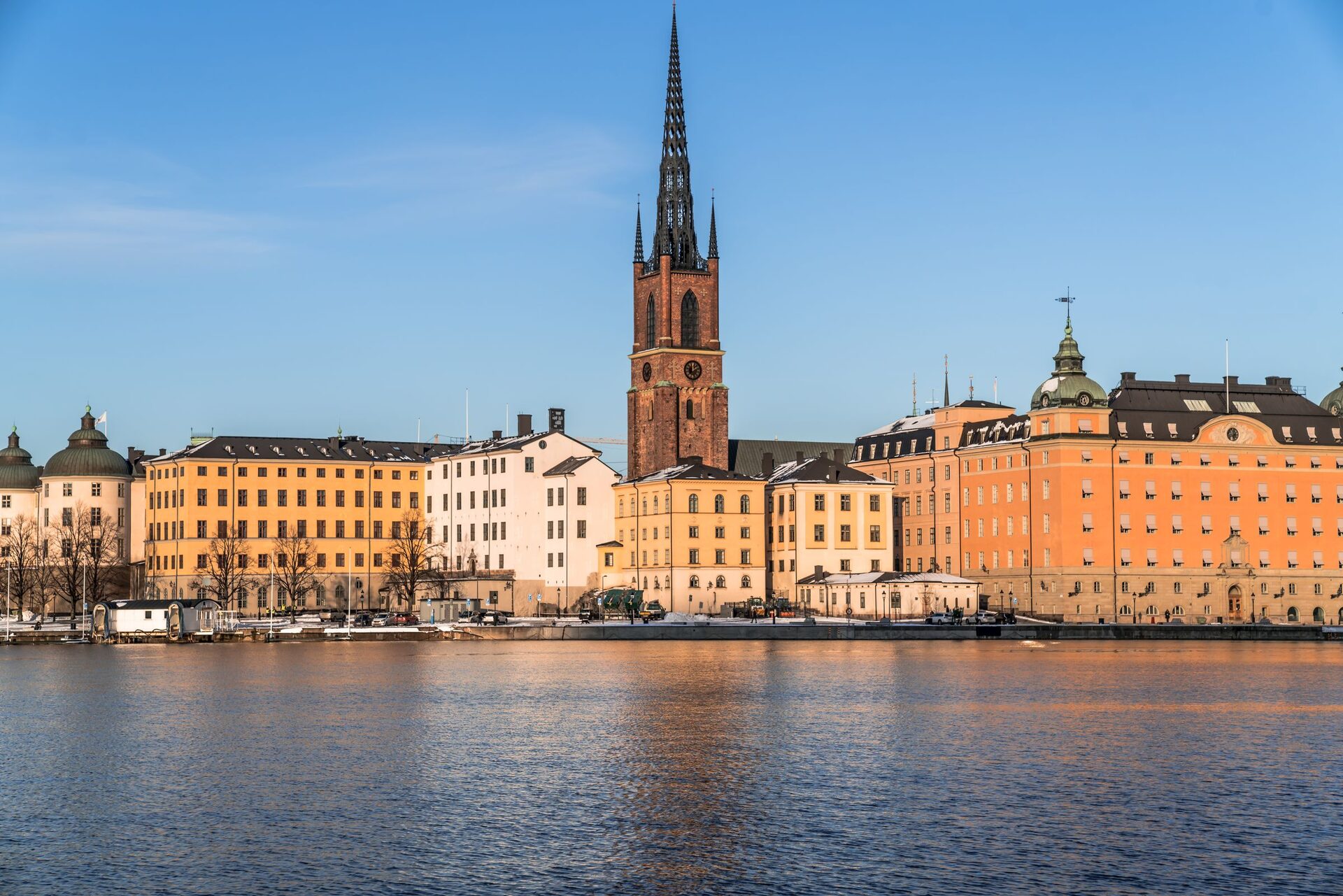 Riddarholmen in Stockholm seen across the water, with the openwork iron spire of Riddarholm Church above yellow and orange palaces