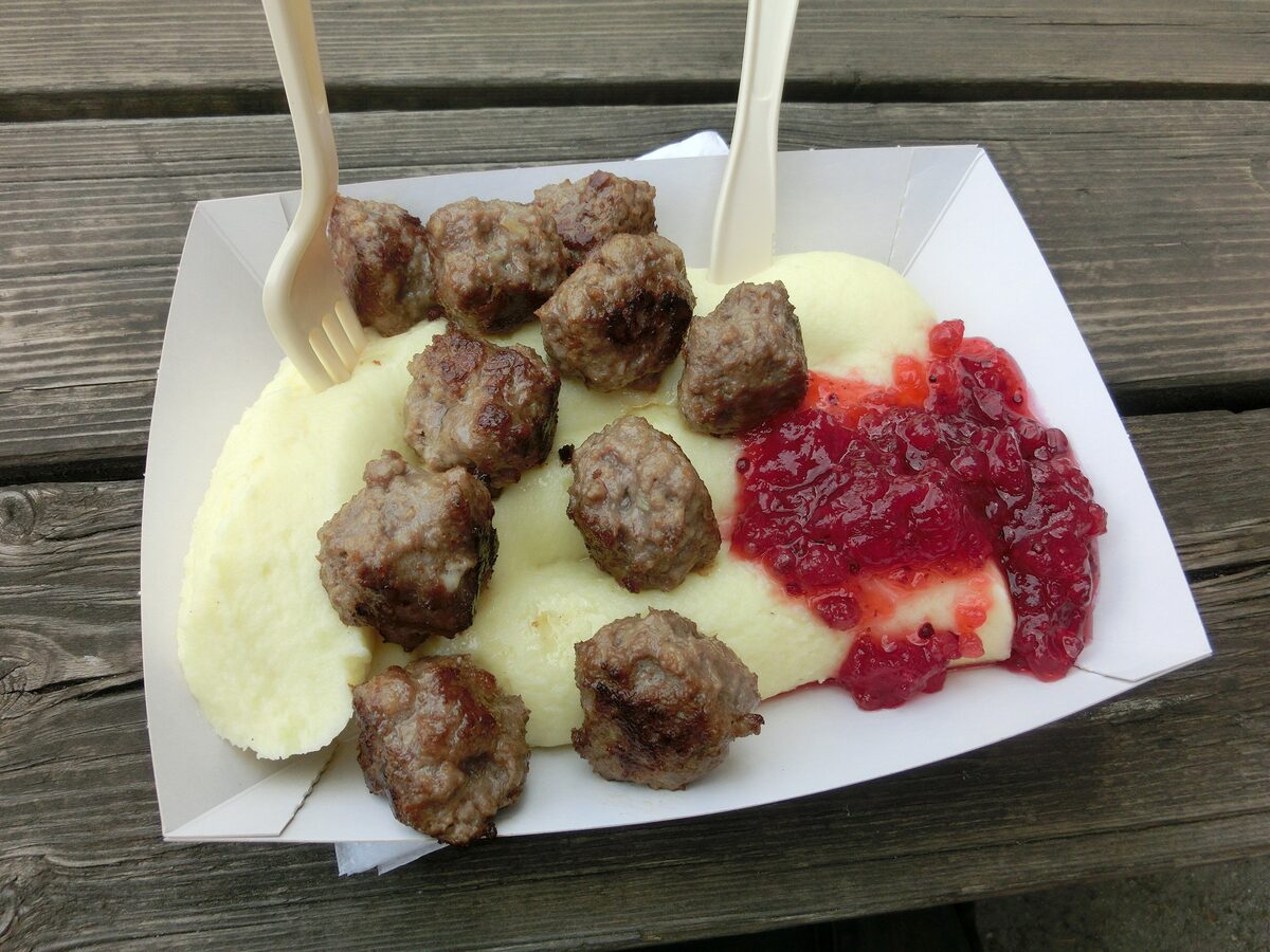 Swedish meatballs with mashed potatoes and lingonberry jam in a paper tray on a wooden table