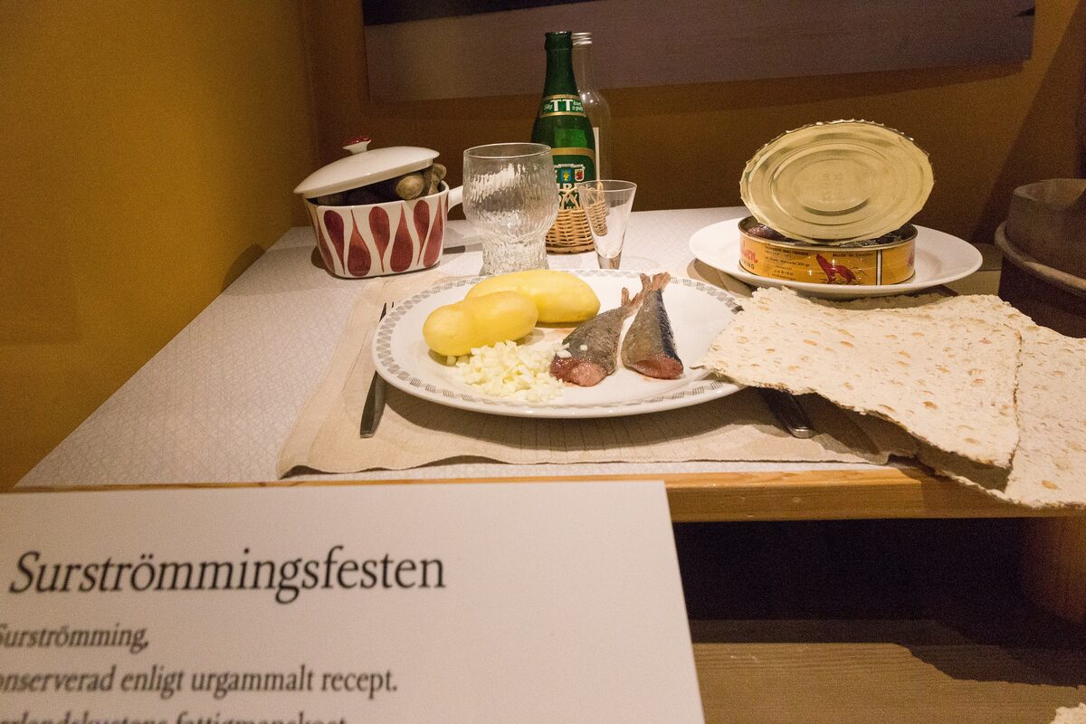 A museum display of a surströmming meal: a can of fermented herring, fish fillets, potatoes and thin flatbread