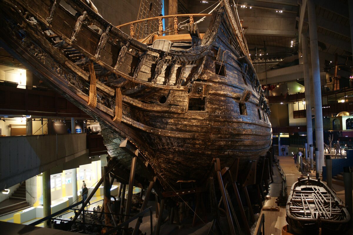 The dark wooden hull and carved stern of the Vasa warship inside the dim hall of the Vasa Museum