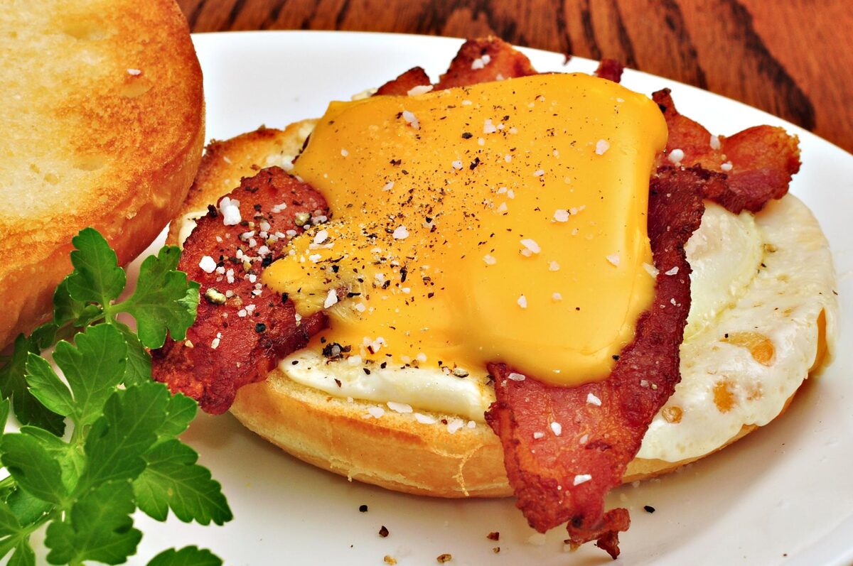 A breakfast sandwich with bacon, fried egg and melted cheese