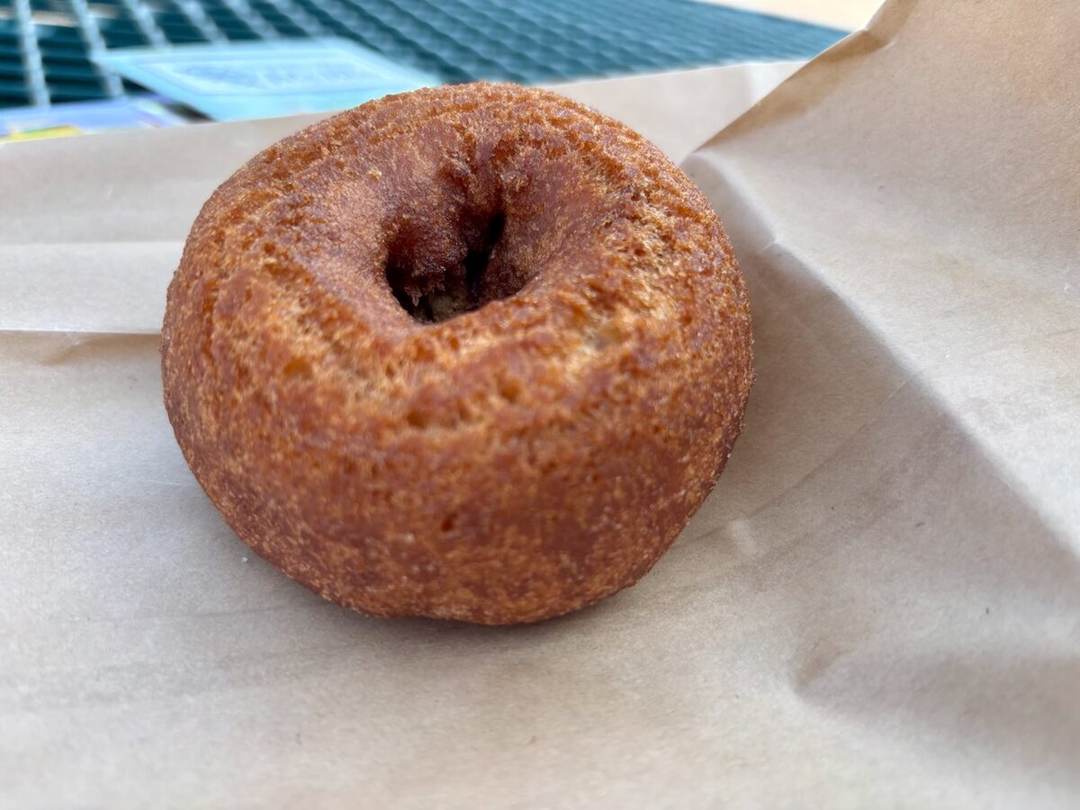 A round cider doughnut with a crisp crust on paper
