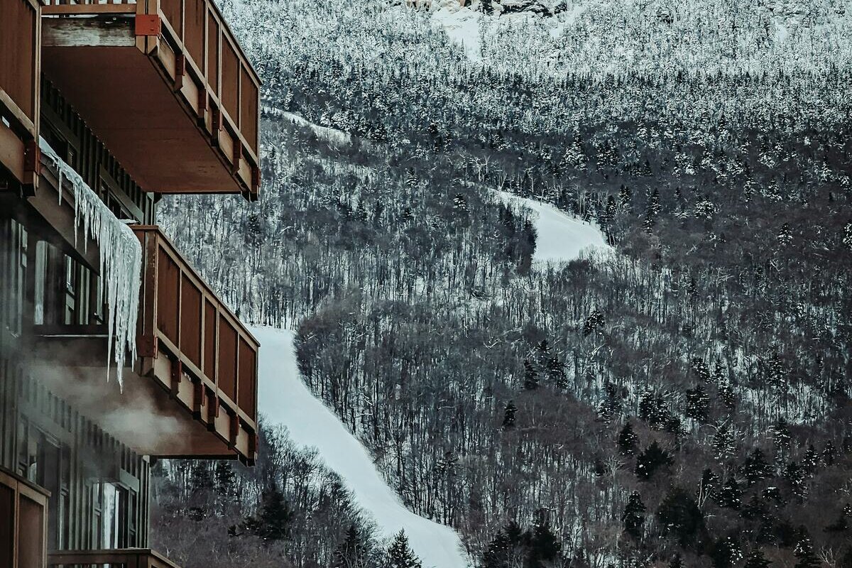 Groomed trail winding through frosted forest past icy lodge balconies