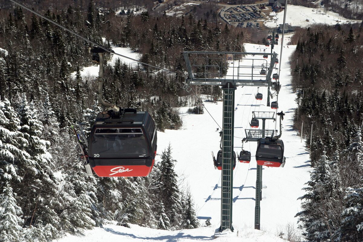 Red gondola cabins climbing through snowy spruce on Mount Mansfield