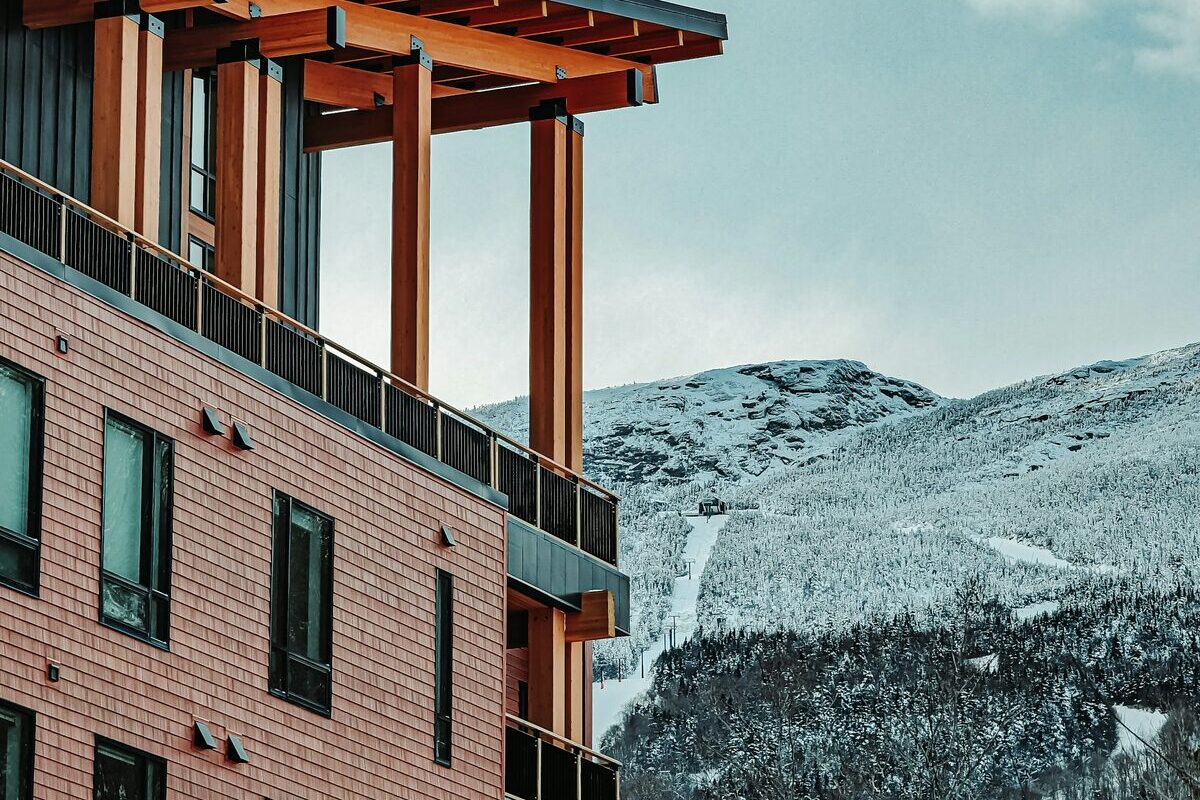 Snowy Mansfield ridge beyond a timber Spruce Peak village building