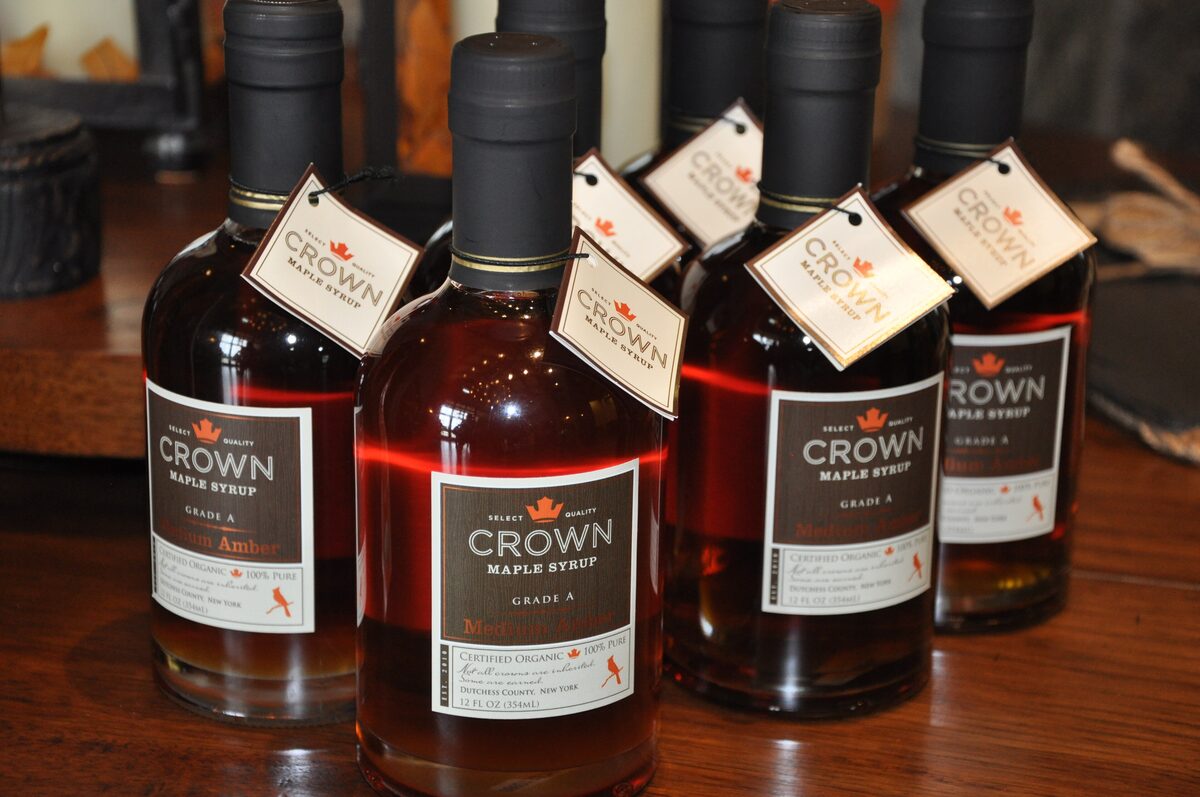 Four bottles of dark maple syrup with paper tags