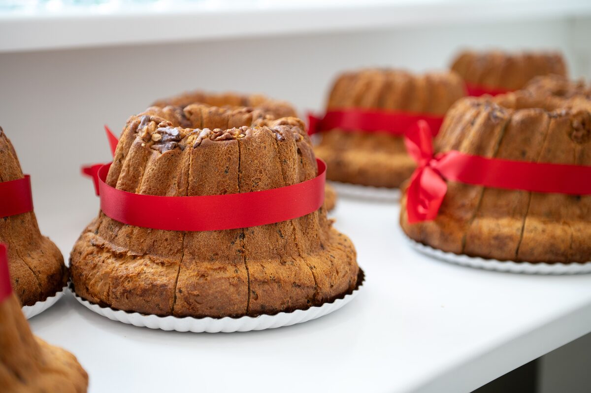 Ring-shaped kougelhopf cakes with red ribbons tied around them, on a white shelf
