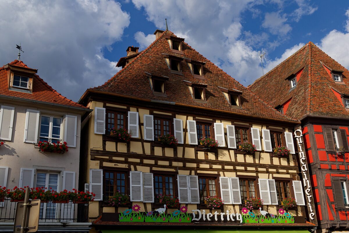Half-timbered houses with flower boxes on a street in Obernai, one of them with a painted sign