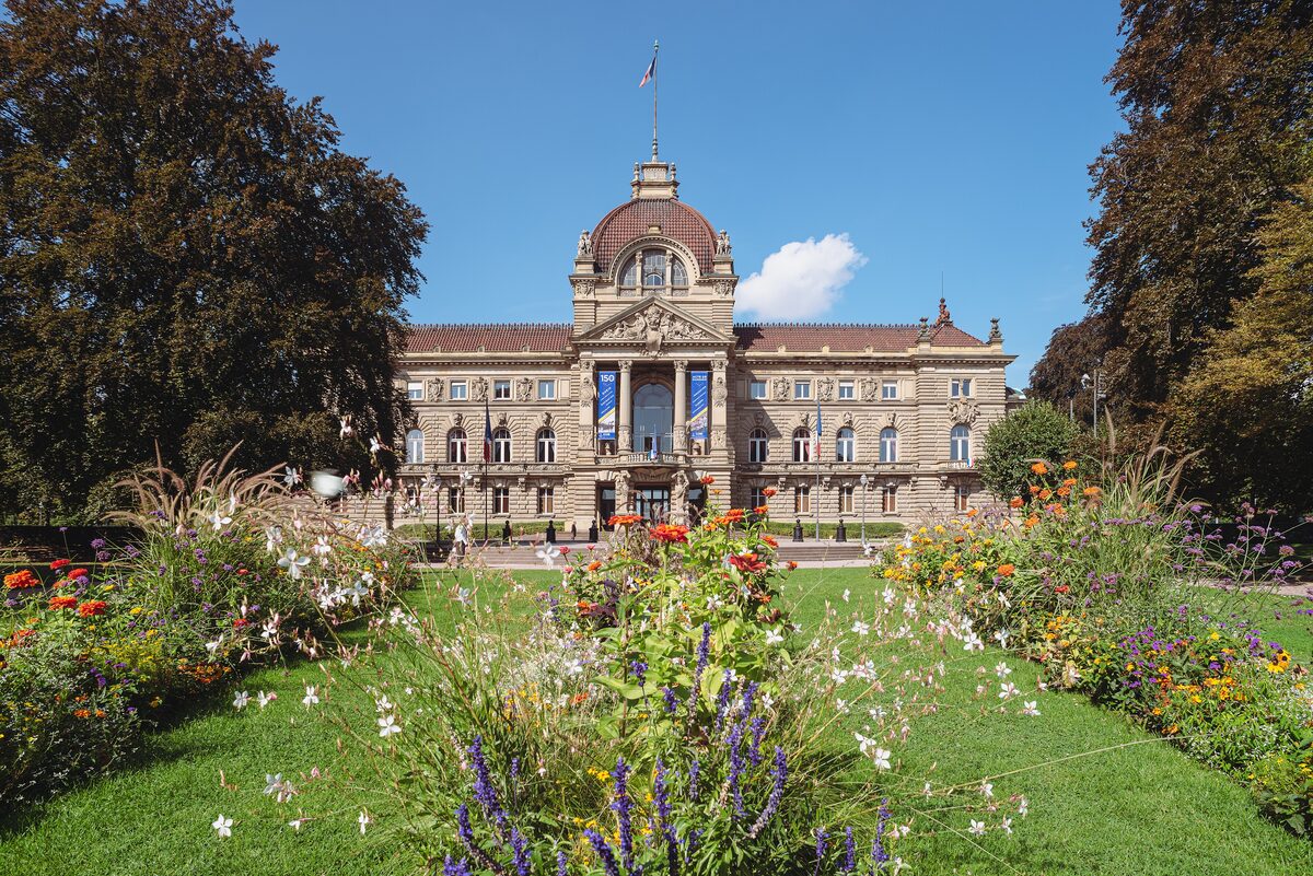 The domed Palais du Rhin, the former imperial palace, across the flower beds of Place de la République under a blue sky