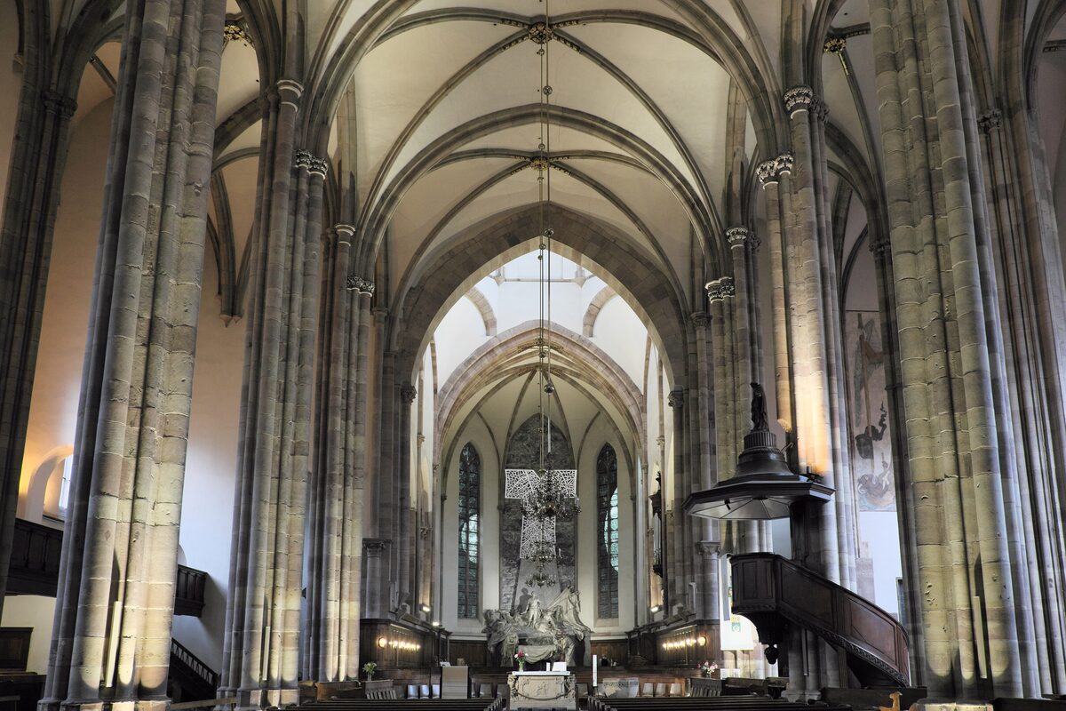 The nave of Saint-Thomas church, a hall church with tall pale pillars and ribbed vaults, looking toward the choir and the pulpit