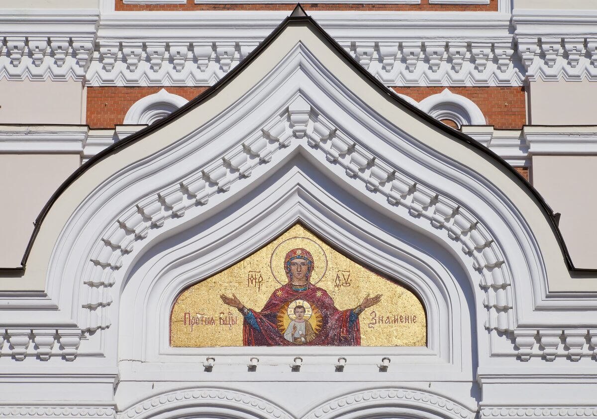 The white facade of Alexander Nevsky Cathedral with a gold Byzantine mosaic over the entrance
