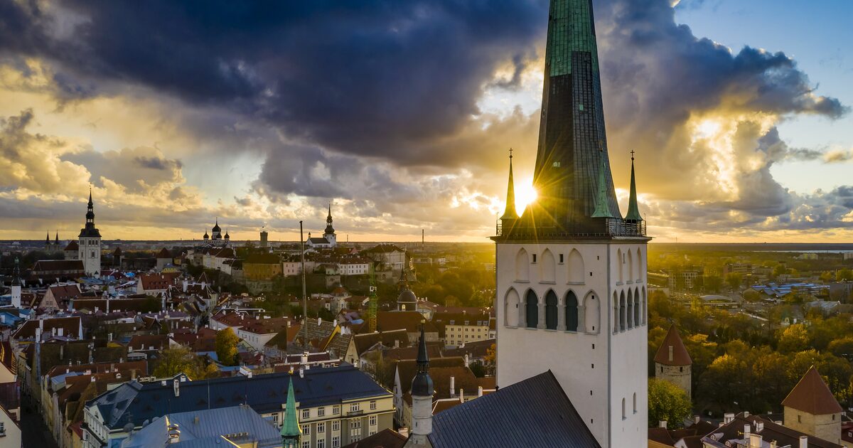 St Olaf's spire rising over the red roofs of Tallinn Old Town at sunset, seen from the air