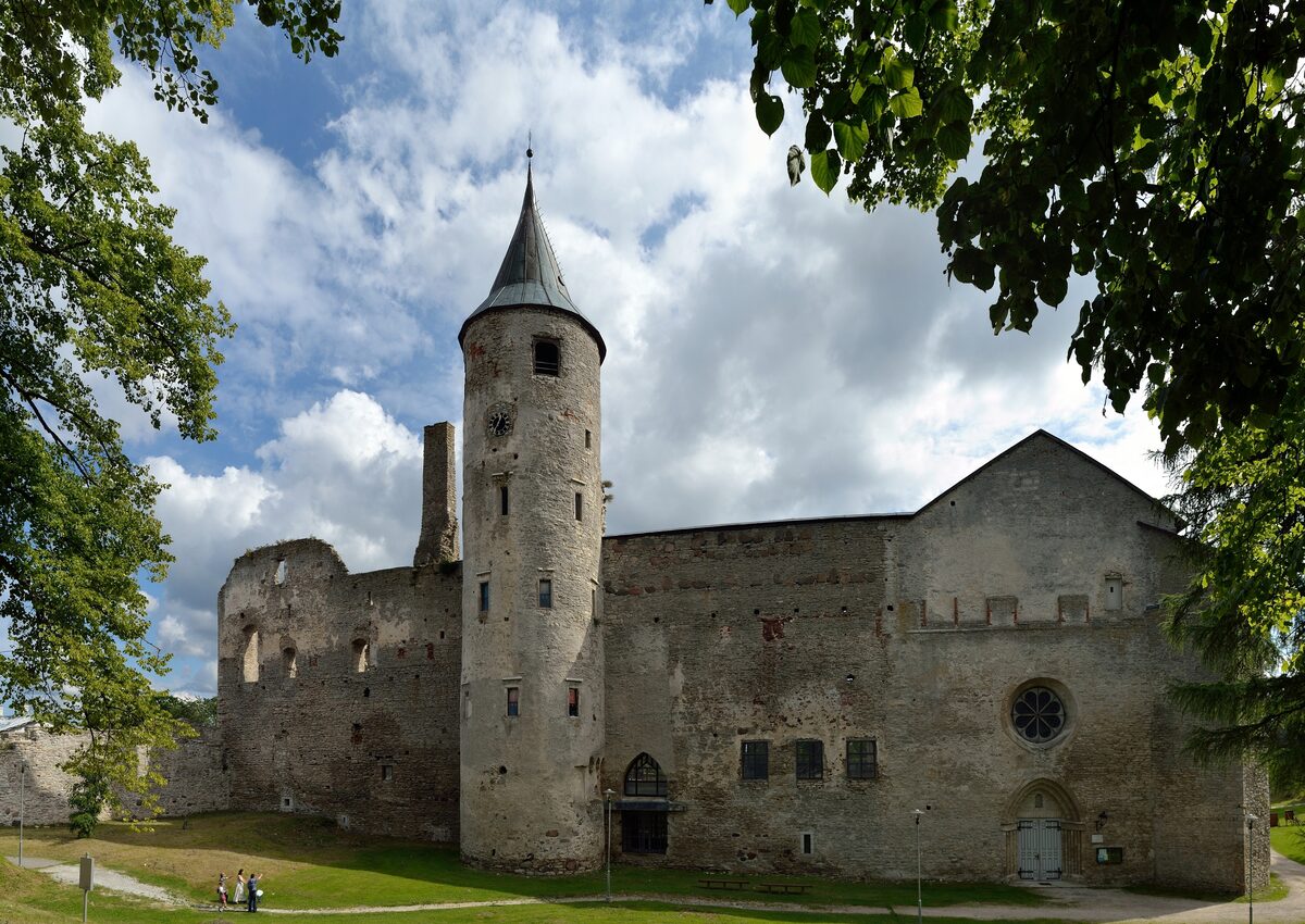 The round tower and stone walls of Haapsalu's bishop's castle framed by trees under a cloudy sky
