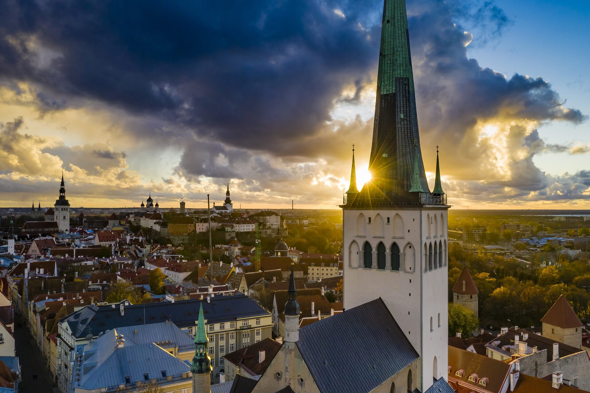 St Olaf's spire rising over the red roofs of Tallinn Old Town at sunset, seen from the air