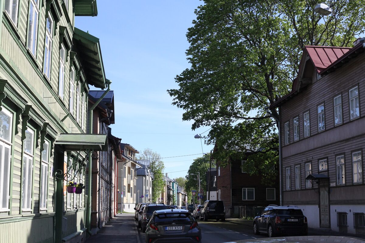Two-storey wooden houses with painted trim along a tree-lined street in Kalamaja