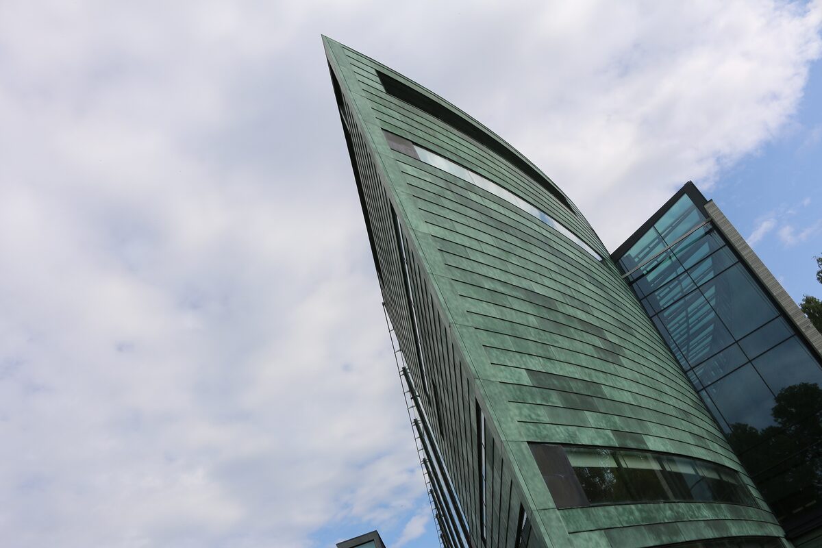 The angled green copper roof and glass wing of the Kumu Art Museum against a cloudy sky
