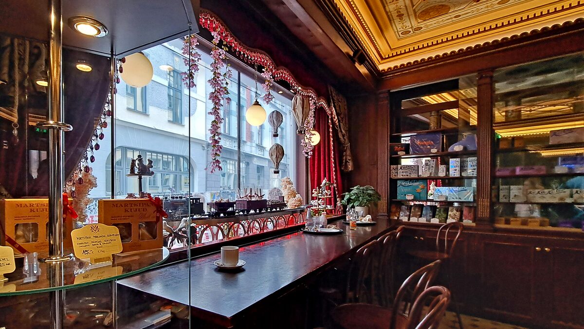 The dark wood counter, brass fittings and gilded ceiling of the Maiasmokk cafe interior beside a street window