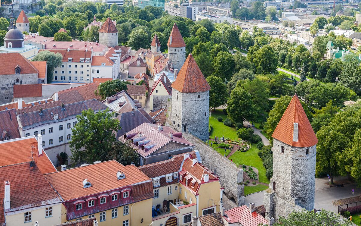 Orange-roofed Old Town wall towers and a green park among red rooftops, seen from the tower of St Olaf's Church