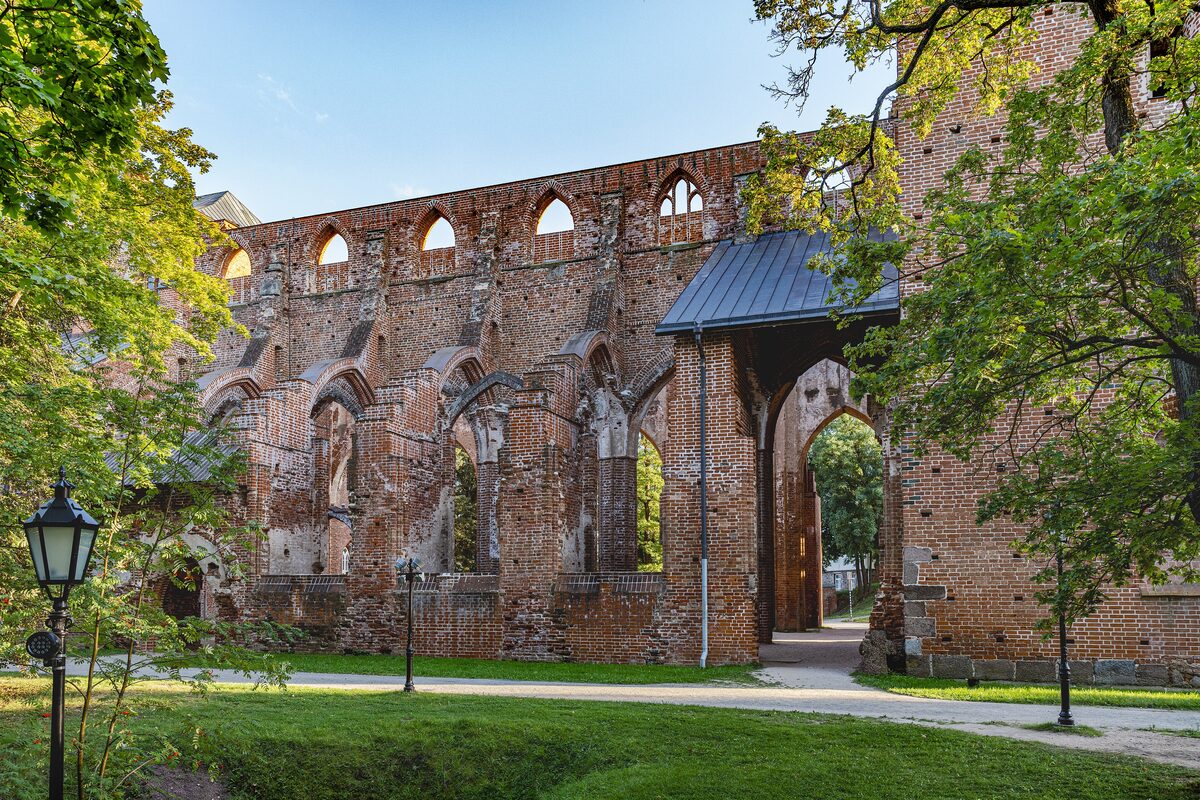 The red-brick ruins of Tartu Cathedral with tall Gothic windows among trees on Toome Hill