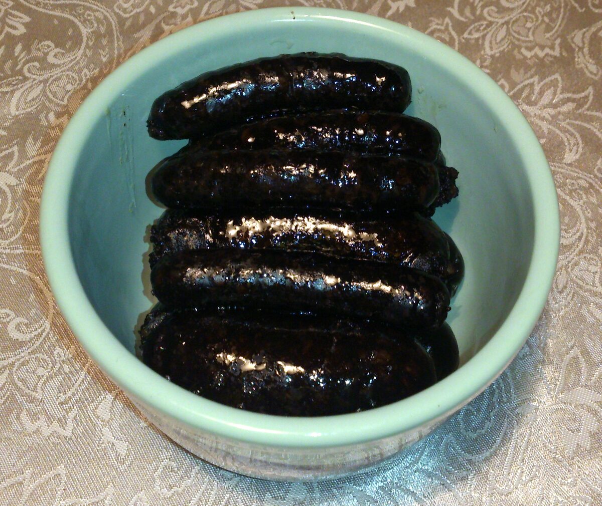 Dark blood sausages coiled in a pale green bowl