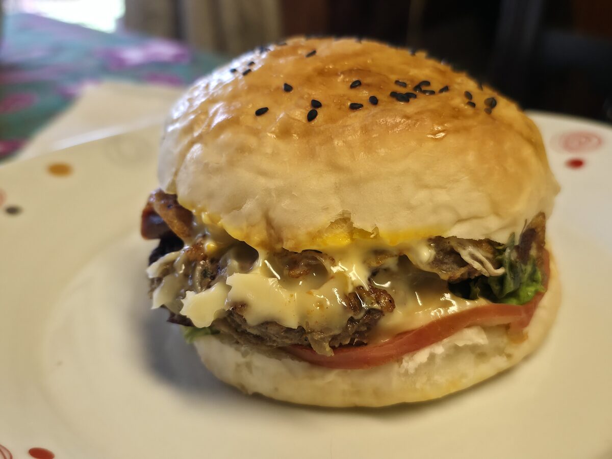 A cheeseburger with melted cheese and tomato in a sesame bun