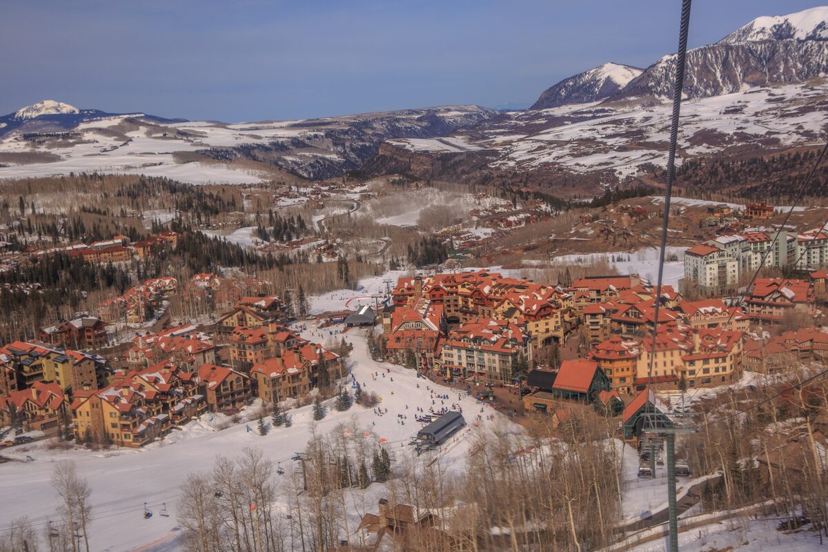 Gondola cable above the red-roofed buildings and ski run of Mountain Village