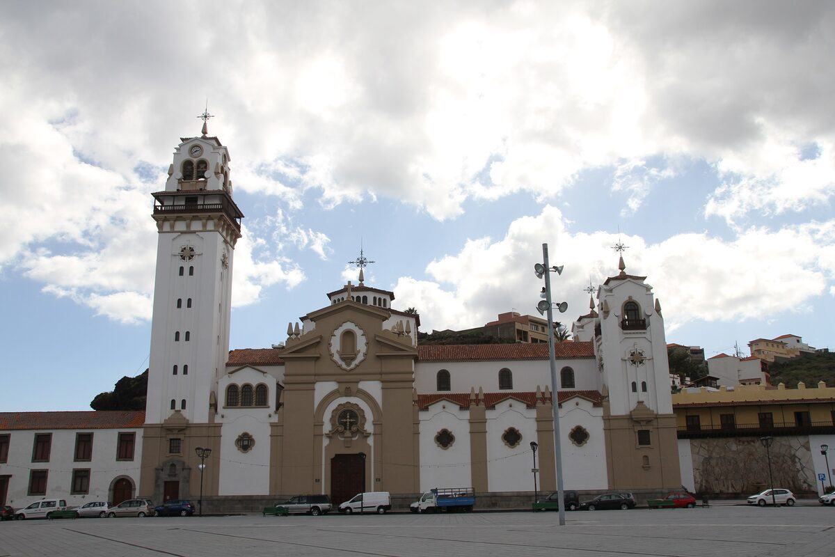 The Basilica of Candelaria, with its tall white bell tower and sand-colored facade on the square