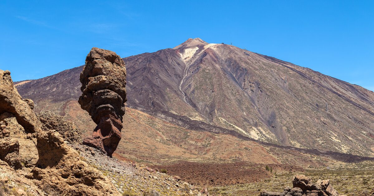 Teide under a clear blue sky, with the Roque Cinchado rock tower of the Roques de García in the foreground