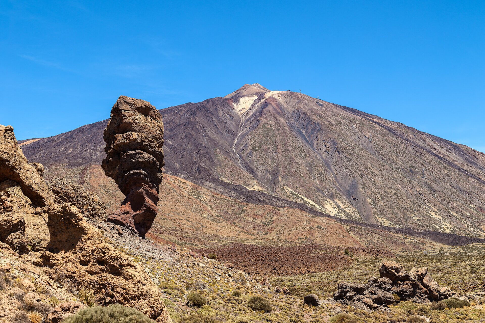 Teide under a clear blue sky, with the Roque Cinchado rock tower of the Roques de García in the foreground