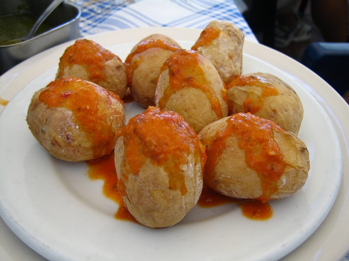 Wrinkled salted potatoes topped with red mojo on a white plate
