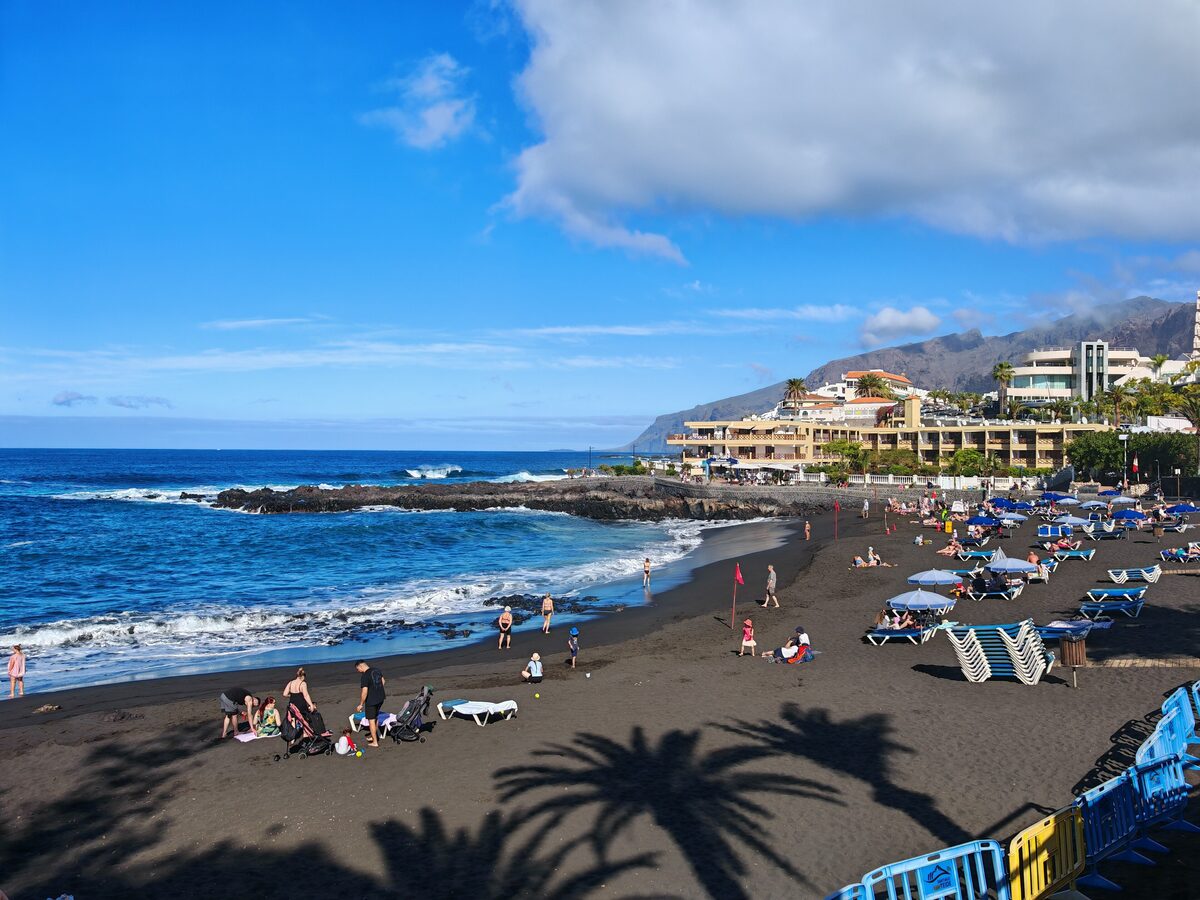 Playa de la Arena with black sand, parasols and surf breaking on the shore