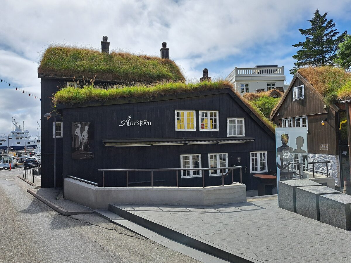 The turf-roofed black wooden house of Áarstova restaurant in Tórshavn, with its name on the wall