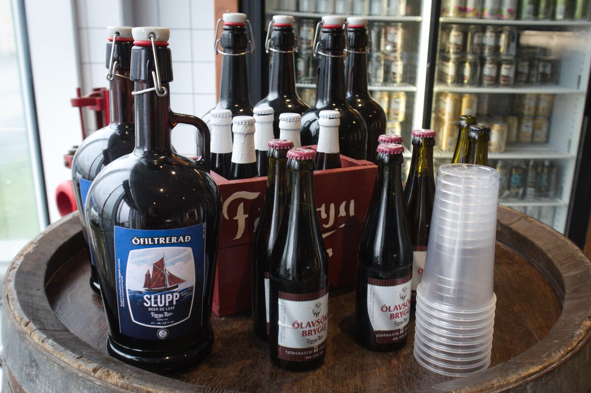 Bottles of Föroya Bjór beer on a wooden barrel in Klaksvík, with a red crate behind