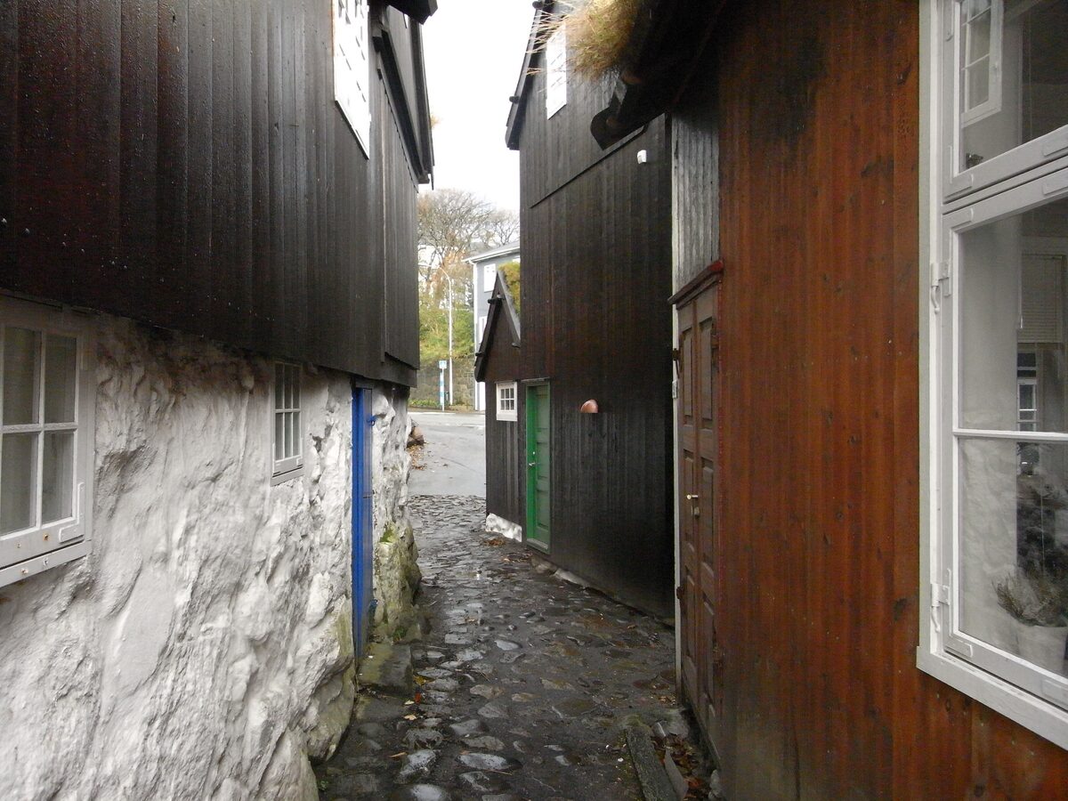 A narrow cobbled lane on Gongin in Tórshavn's old town, between whitewashed stone and black timber walls