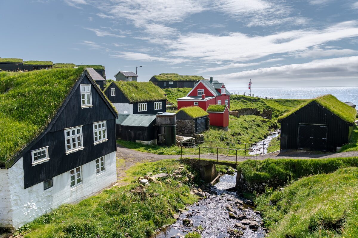 The turf-roofed houses of the Mykines settlement on a grassy slope above the sea