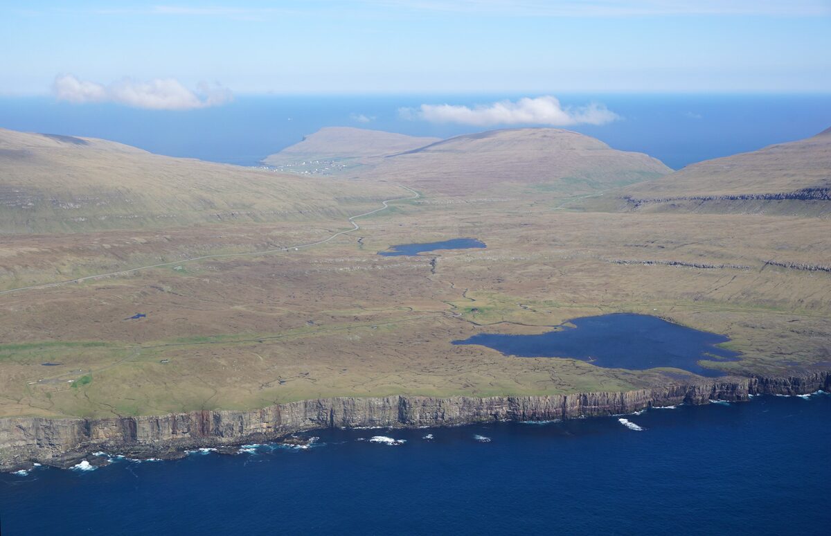 Aerial view of Sandur on Sandoy, with two lakes and a cliff coast beyond