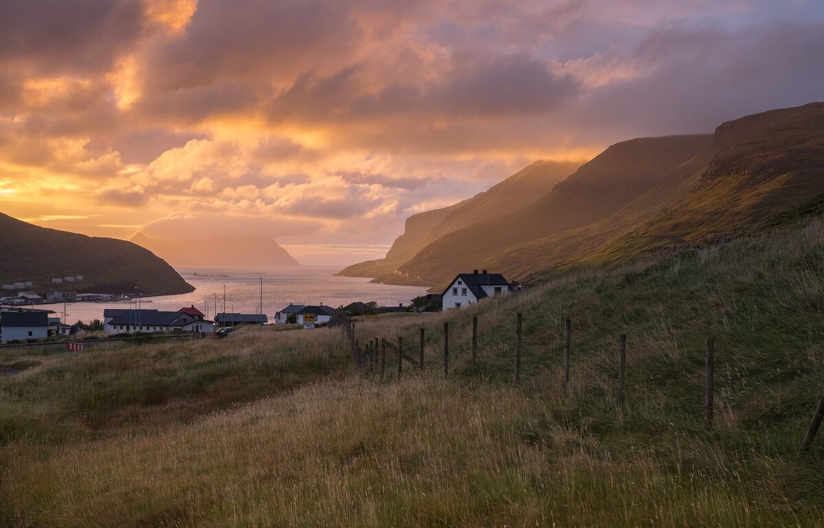 Sunset over the houses of Sørvágur on Vágar, with the sea and cliffs behind