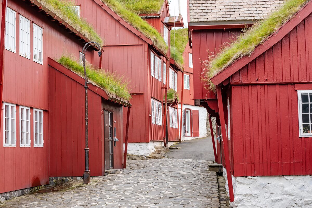 Turf-roofed red wooden houses along a cobbled lane on Tinganes in Tórshavn