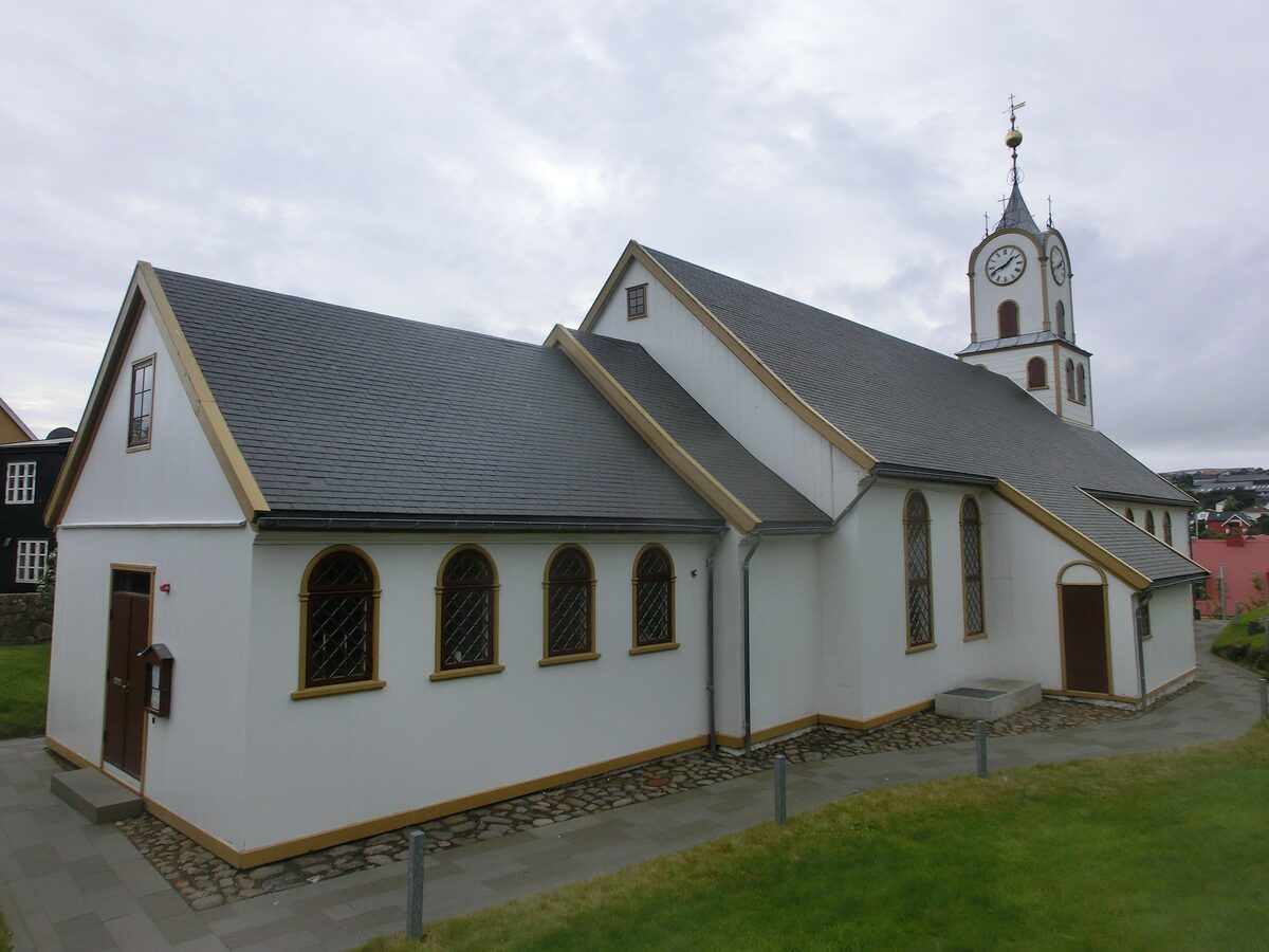 The white Havnar Kirkja cathedral in Tórshavn with its gold-trimmed arched windows and clock tower