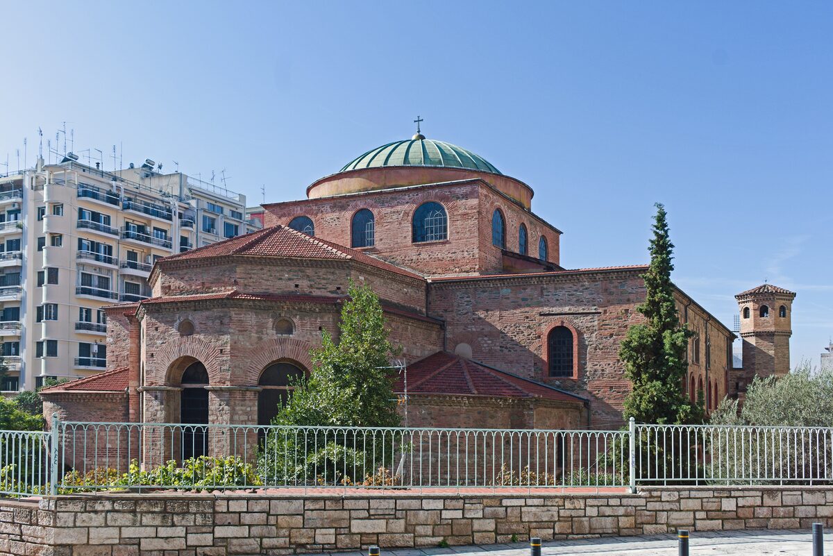 The brick Byzantine church of Hagia Sophia in Thessaloniki with its green dome, seen from the east over its garden railings