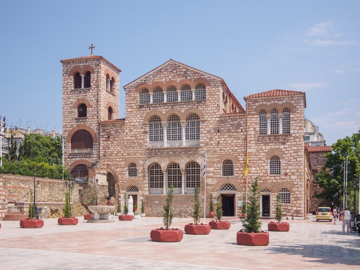 The facade of the Basilica of Hagios Demetrios with its brick and stone walls, arched windows and square bell tower on a sunny morning