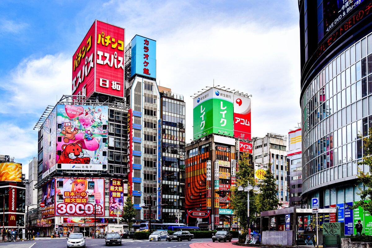 Akihabara's Electric Town on a bright day, with huge billboards and shop towers lining the crossing