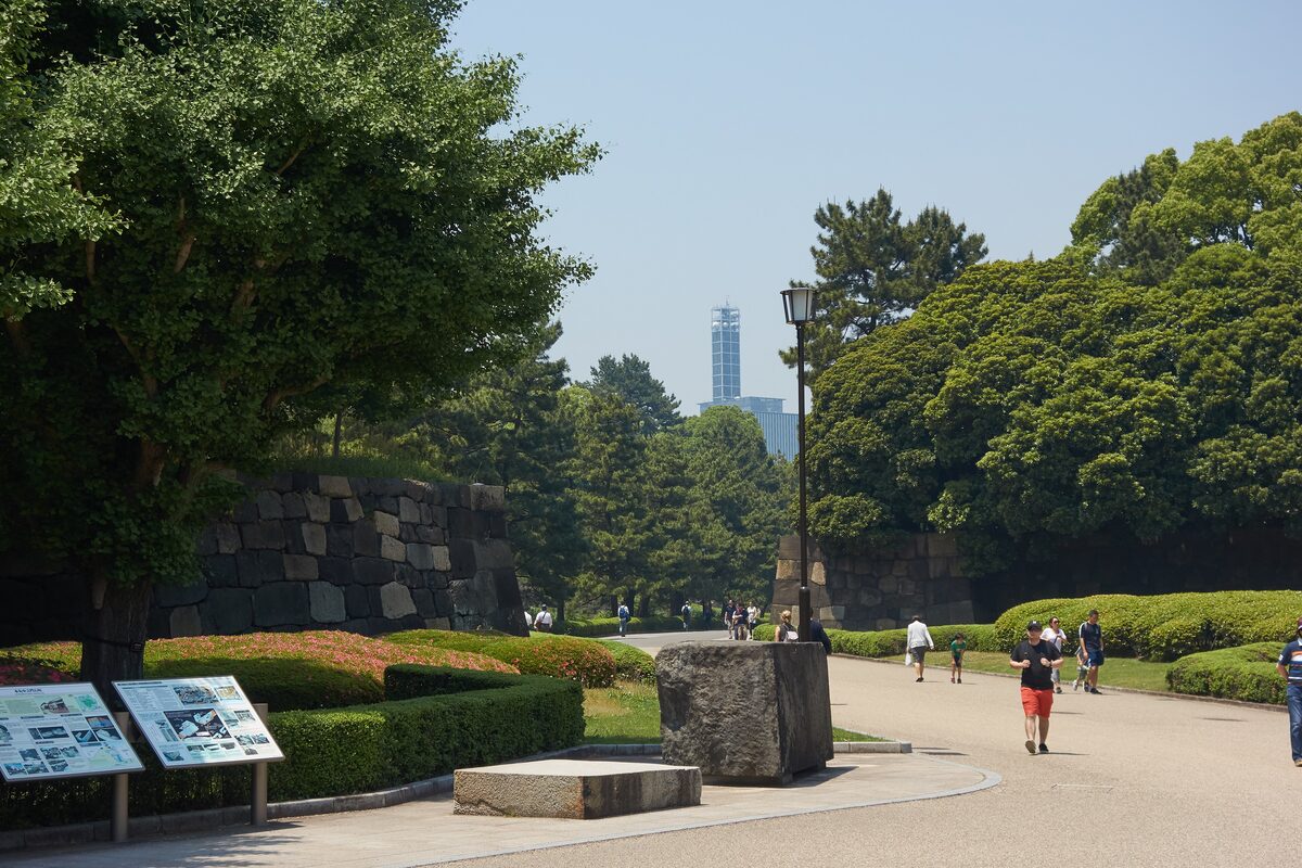 Stone walls and a wide gravel path inside the Imperial Palace grounds, with visitors walking along it