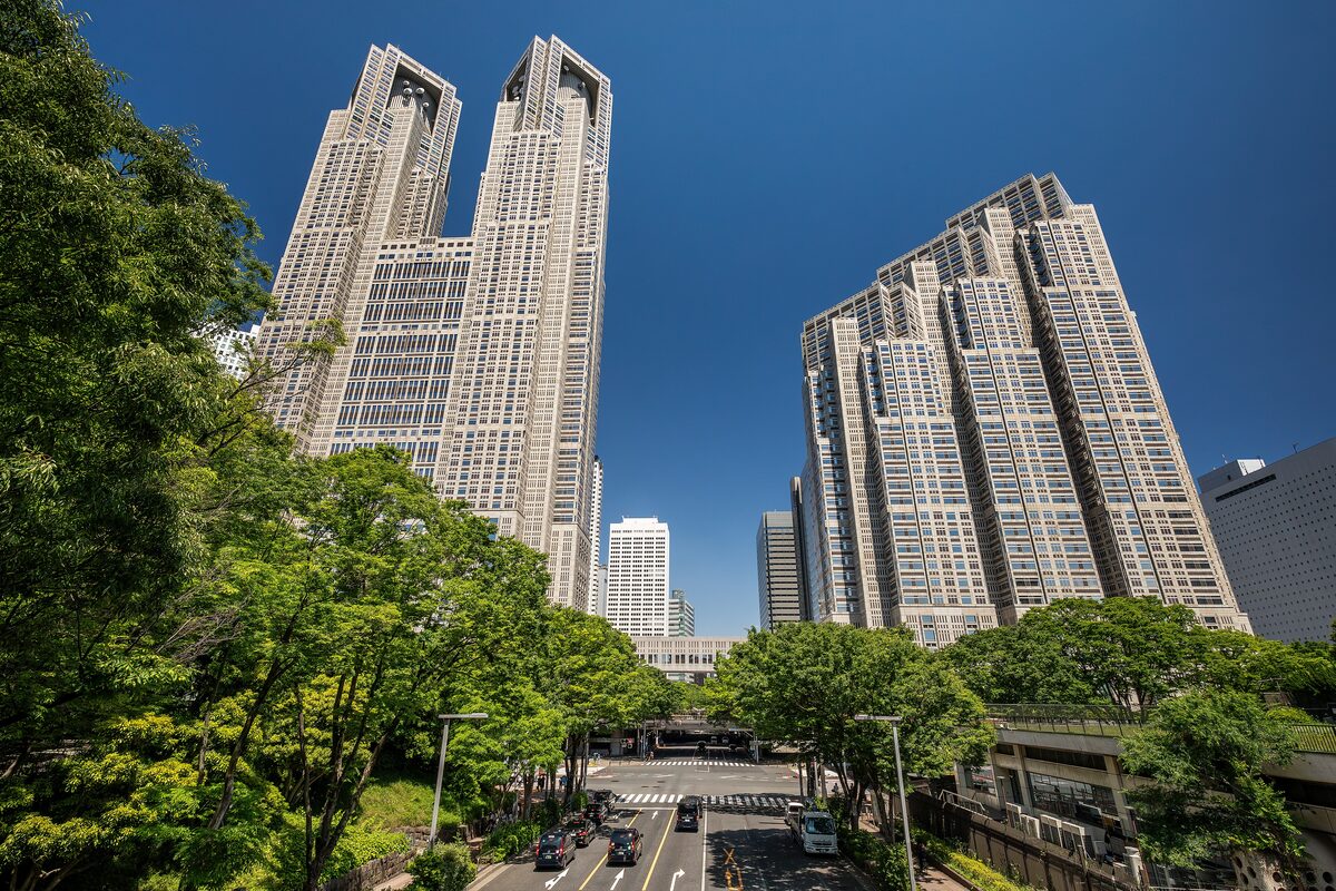 The twin towers of the Tokyo Metropolitan Government Building rising above trees on a clear day