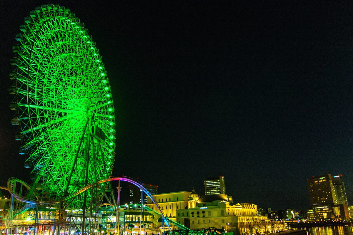 The green-lit Ferris wheel at Minato Mirai in Yokohama at night, beside the waterfront