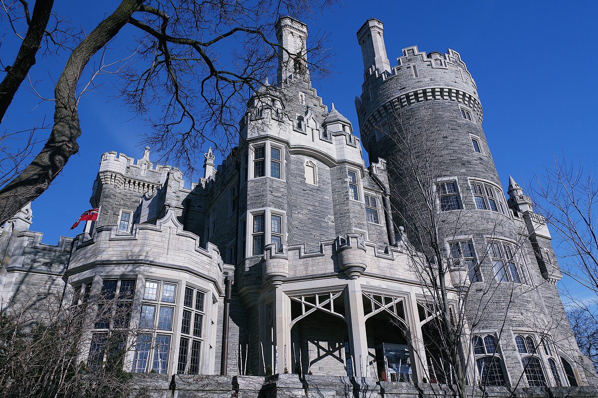 Casa Loma's gray stone towers and turrets against a deep blue sky