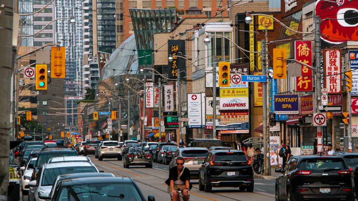 A busy Spadina Avenue in Chinatown with Chinese-language signs above the shopfronts and traffic below
