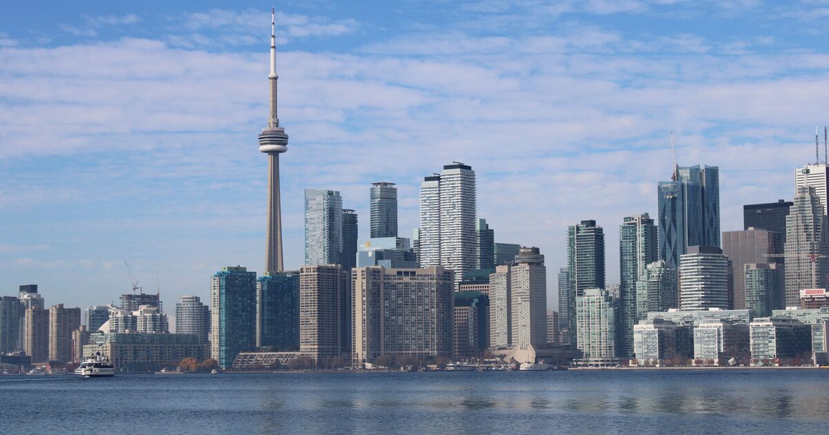 The Toronto skyline with the CN Tower rising above the downtown towers and Lake Ontario in the foreground